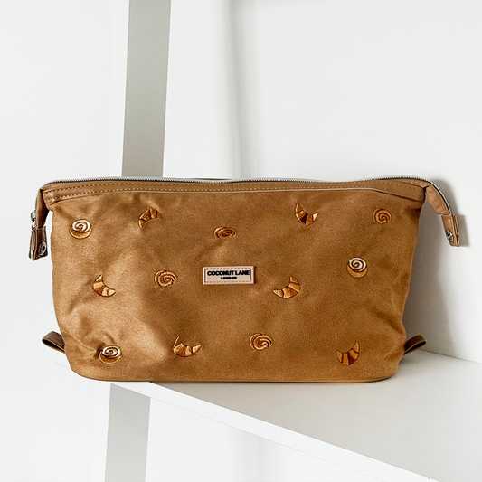 Tan suedette expandable makeup bag with gold accents, featuring Croissant Club text on the front.