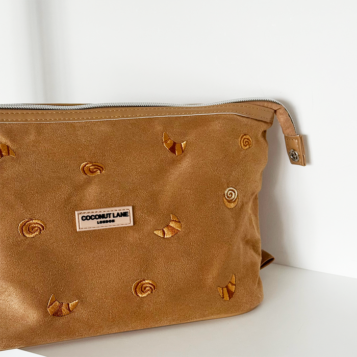 Expandable suedette makeup bag in neutral tones with embroidered croissants and Croissant Club Parisian-themed design.