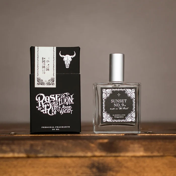 Perfume bottle with clear glass and cap beside matching dark blue product box