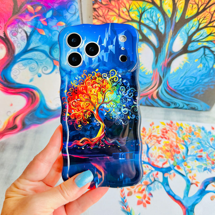 Hand holding The Wishing Tree Wavy Luxe MagSafe iPhone case, showing the deep blue print with a swirling rainbow tree of life.