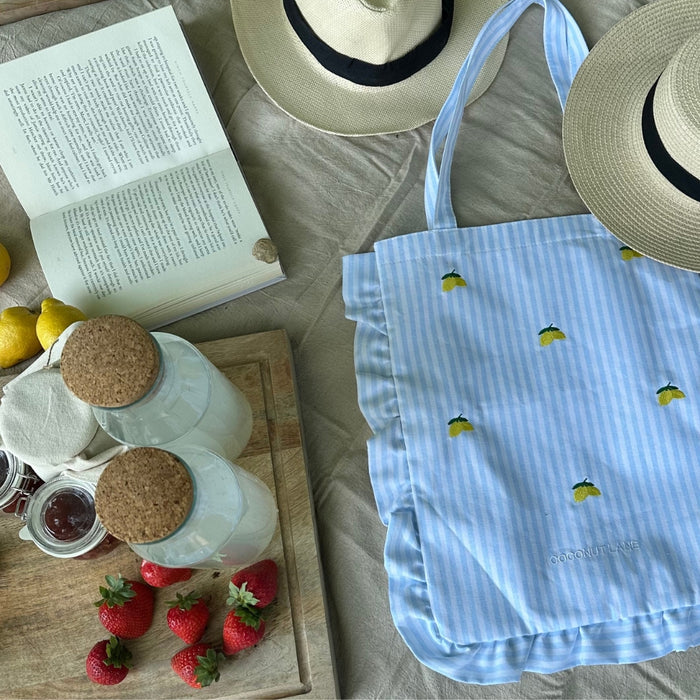 Yellow tote bag with embroidered lemons and sturdy handles, featuring a bright, casual design.