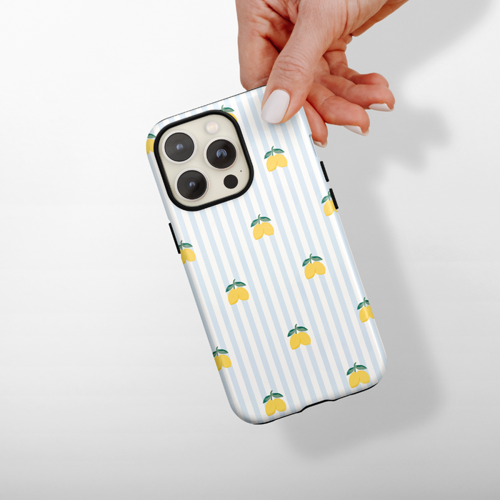 Hand holding a blue striped phone case with yellow lemon pattern from Coconut Lane.