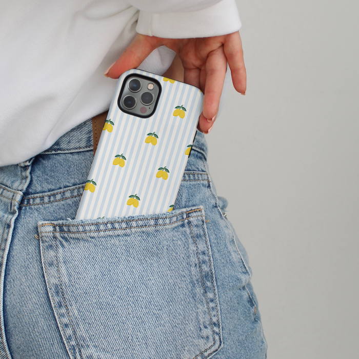 Hand pulling an iPhone from jeans with a Coconut Lane tough phone case featuring blue stripes and yellow lemons.