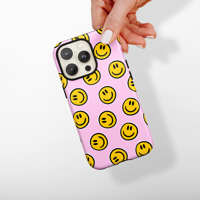 Hand holding a Coconut Lane phone case with yellow smiley faces on a plain white background.