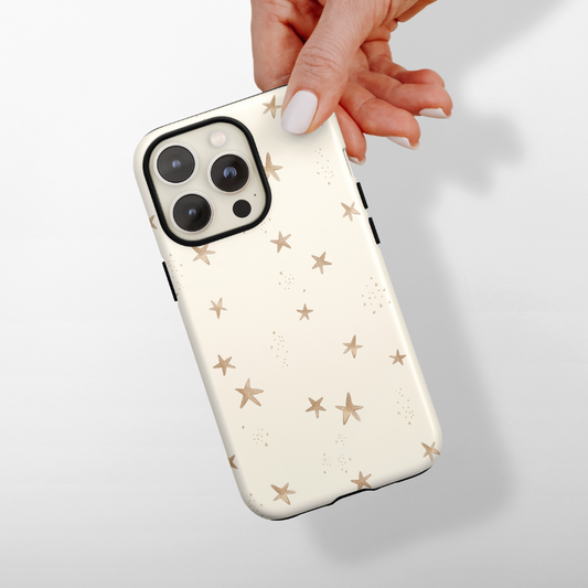 Cream Coconut Lane Tough Phone Case with gold starfish pattern, shown in hand against a white background.