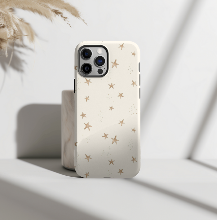 Beige tough phone case with white star pattern on a smartphone, shown in bright natural lighting.