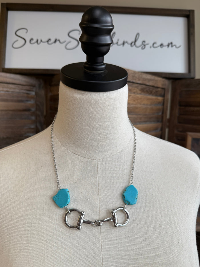 Turquoise chunk snaffle bit necklace on a mannequin with silver-tone rings and chain