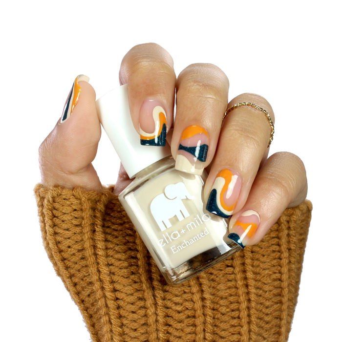 Twilight blue with orange and nude abstract accent nails, holding a nude bottle