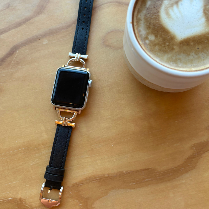 Black smartwatch with a Coconut Lane vegan PU leather strap beside a coffee on a wooden table.