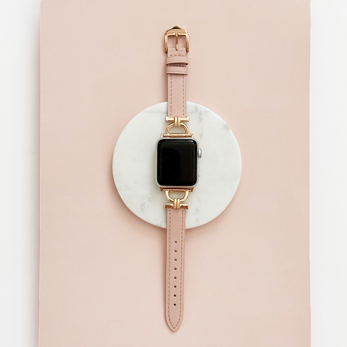 Pink Chai vegan leather Apple Watch strap with gold buckle on a white marble and pink surface.