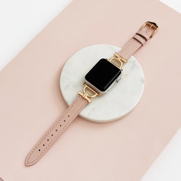 Pink Chai vegan PU leather Apple Watch strap with gold accents on a white marble and pink surface.