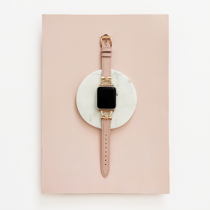 Pink Chai vegan leather Apple Watch strap displayed on a round marble coaster against a pink background.