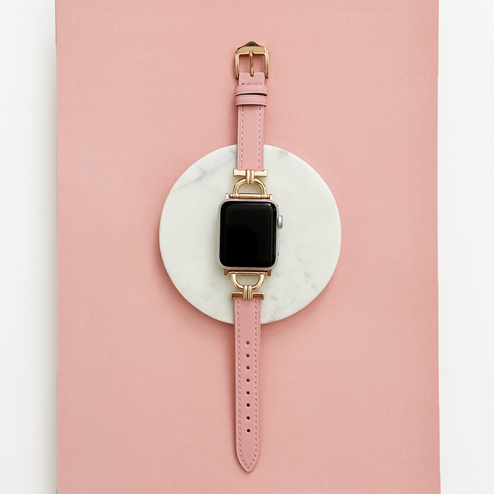 Powder pink vegan PU leather Apple Watch strap with gold buckle on marble and pink background.