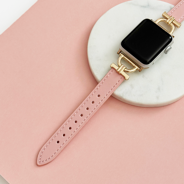Powder pink vegan PU leather Apple Watch strap with gold accents, displayed on a marble coaster.