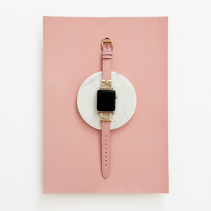 Powder pink vegan PU leather Coconut Lane Apple Watch strap displayed on white marble with a pink background.