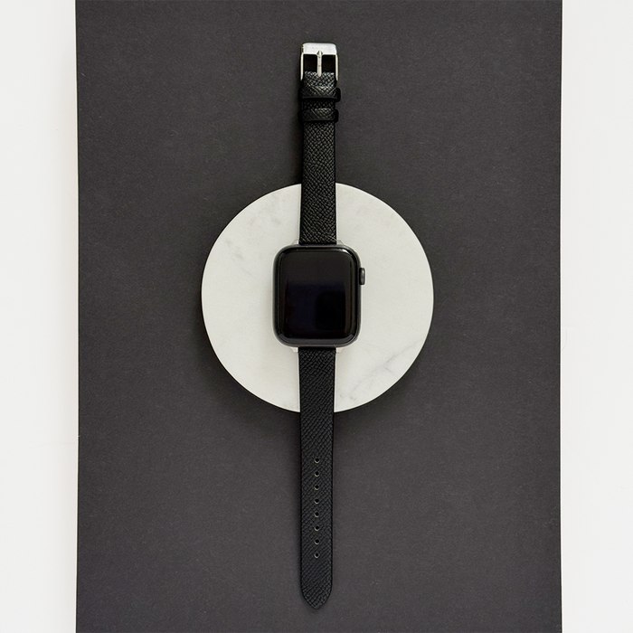Black smartwatch with a Coconut Lane vegan textured PU leather strap on a white round surface.