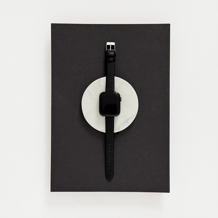Black vegan textured PU leather Apple Watch strap displayed on white marble against a black background.