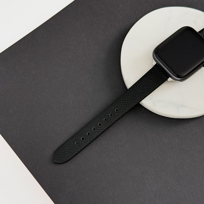 Black smartwatch with a textured vegan leather Coconut Lane strap on a white tray.