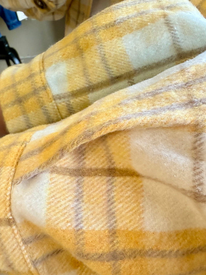 Yellow plaid shacket fabric close-up with cuff seam